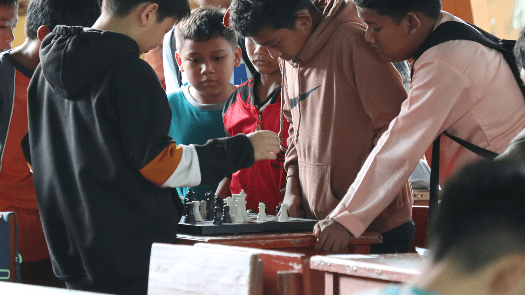 Teen students gathered around a chess set during a classroom game